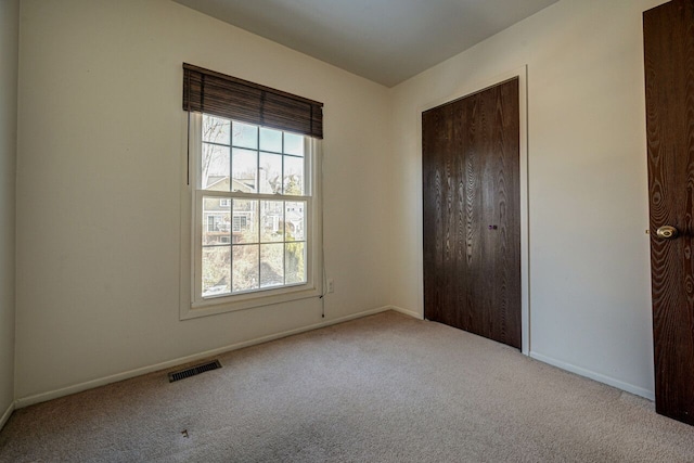 unfurnished bedroom featuring multiple windows, carpet, visible vents, and baseboards