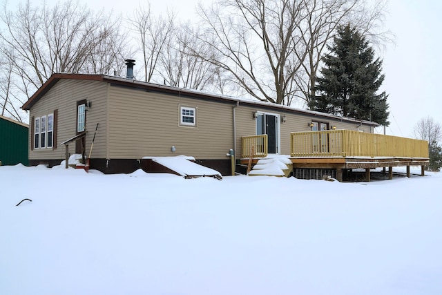 snow covered back of property with a wooden deck