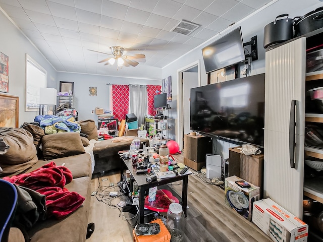 living room featuring ceiling fan, ornamental molding, wood finished floors, and visible vents