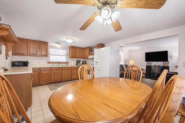 tiled dining area with sink, a textured ceiling, and ceiling fan
