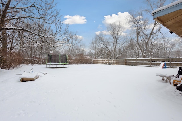 snowy yard featuring a trampoline