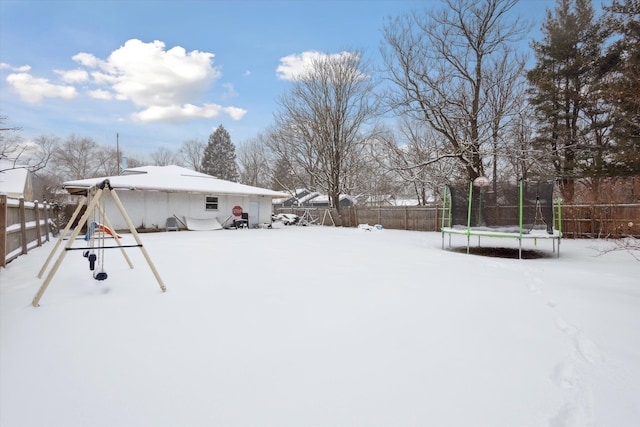 yard layered in snow featuring a playground and a trampoline