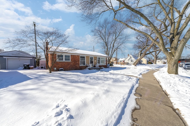 view of front of house featuring a garage, brick siding, and an outbuilding