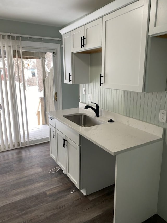 kitchen featuring dark hardwood / wood-style floors, white cabinetry, sink, and light stone counters