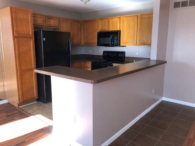 kitchen featuring dark tile patterned floors, kitchen peninsula, and black appliances