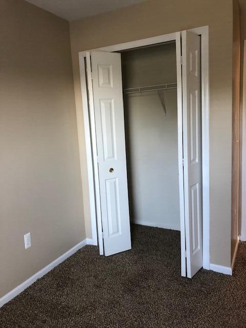 unfurnished bedroom featuring a closet and dark colored carpet