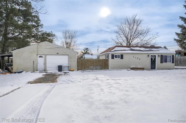 snow covered garage featuring fence