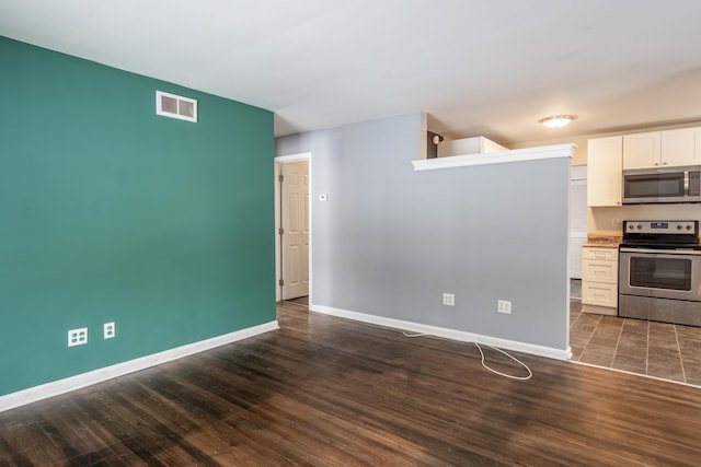 kitchen featuring dark wood-style floors, stainless steel appliances, visible vents, white cabinets, and baseboards