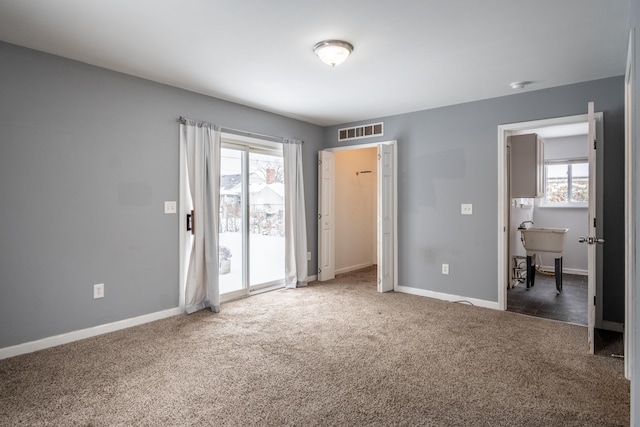 unfurnished bedroom with dark colored carpet, access to outside, visible vents, and baseboards