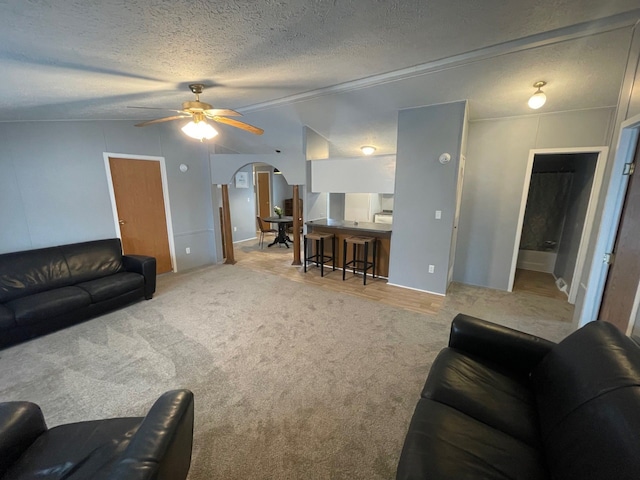 carpeted living room featuring a textured ceiling, lofted ceiling, and ceiling fan