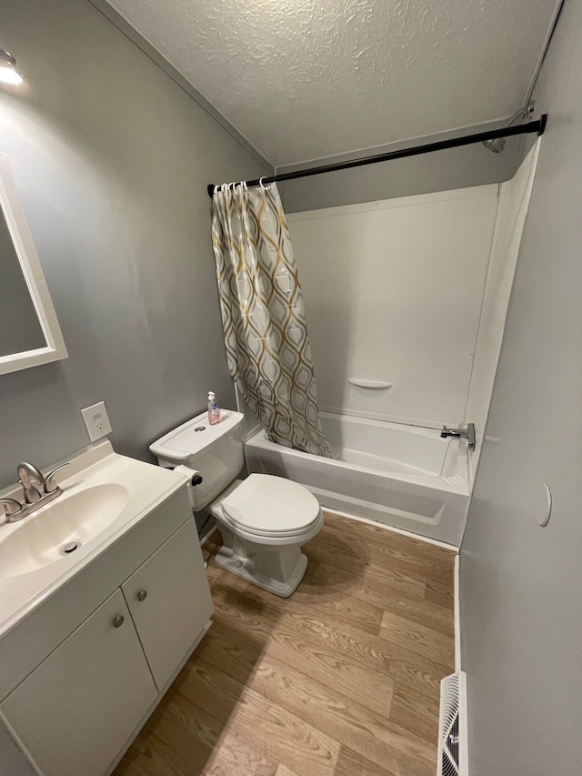 full bathroom with hardwood / wood-style flooring, shower / bath combo with shower curtain, toilet, a textured ceiling, and vanity