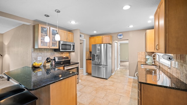 kitchen with hanging light fixtures, appliances with stainless steel finishes, glass insert cabinets, a sink, and a peninsula