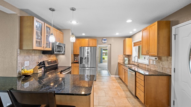 kitchen featuring pendant lighting, appliances with stainless steel finishes, glass insert cabinets, a sink, and a peninsula