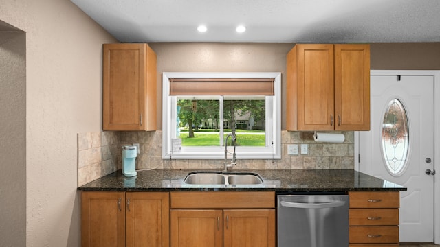 kitchen featuring brown cabinets, backsplash, a sink, dark stone counters, and dishwasher