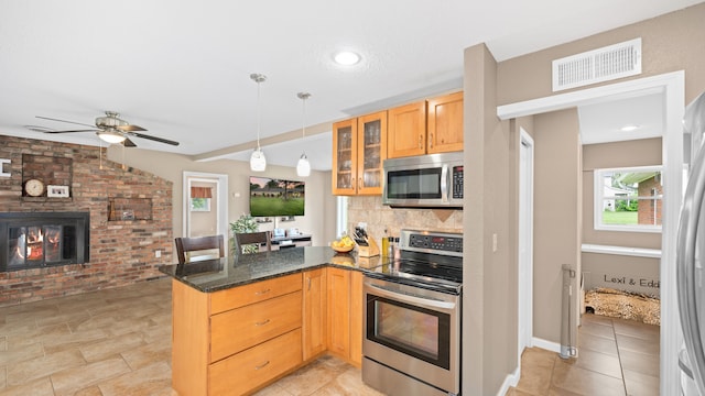 kitchen with a peninsula, visible vents, appliances with stainless steel finishes, dark stone countertops, and glass insert cabinets