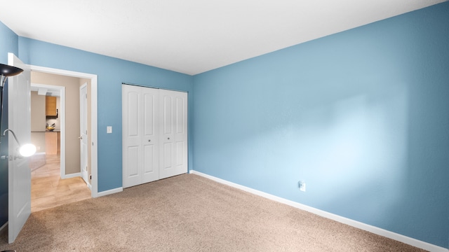 unfurnished bedroom with carpet floors, a closet, and baseboards