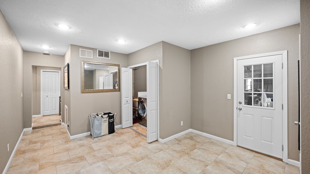 interior space featuring baseboards, visible vents, washer / clothes dryer, and a textured ceiling