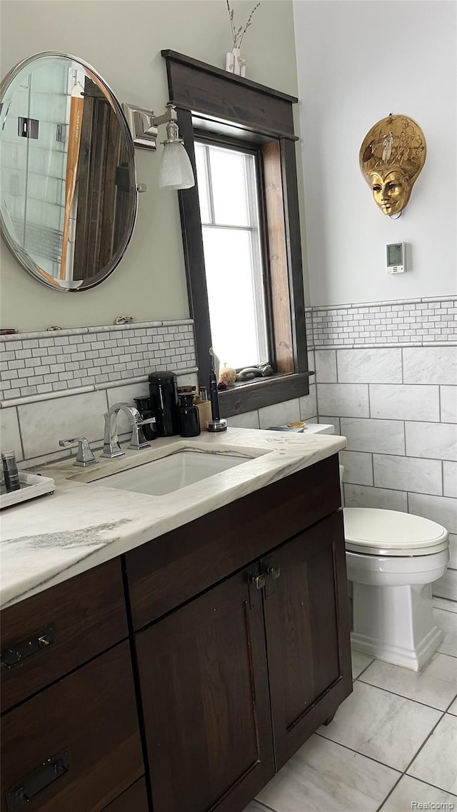 11720 Easy St, Kewadin, MI 49648 - bathroom with tile walls, tile patterned flooring, vanity, toilet, and wainscoting