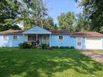 single story home with a garage, a porch, and a front yard