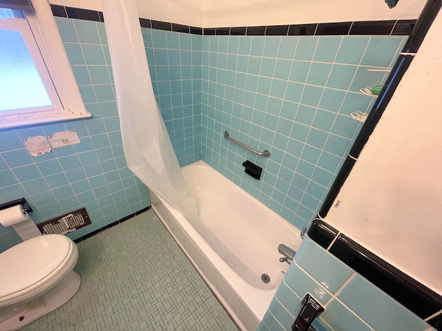 bathroom featuring tile walls, tile patterned floors, shower / bath combo with shower curtain, and toilet