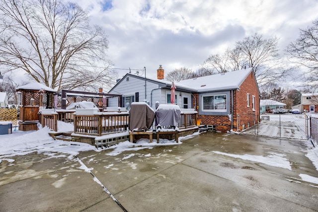 snow covered back of property featuring a wooden deck