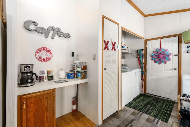 laundry room featuring hardwood / wood-style flooring, ornamental molding, and washing machine and clothes dryer