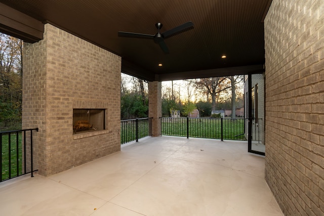 patio terrace at dusk featuring an outdoor brick fireplace and ceiling fan