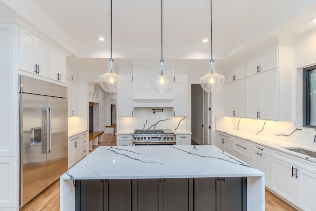 kitchen with high quality appliances, a center island, pendant lighting, and white cabinets