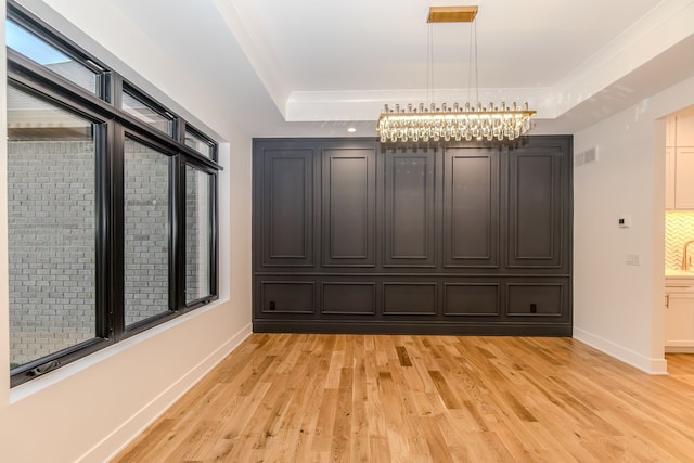 unfurnished dining area featuring light hardwood / wood-style flooring and a raised ceiling