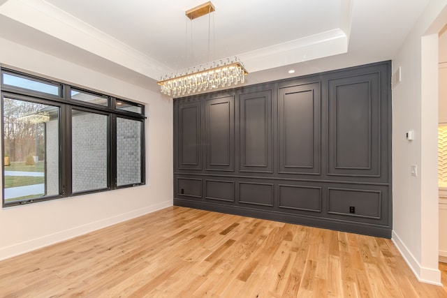 interior space with a raised ceiling and light hardwood / wood-style floors