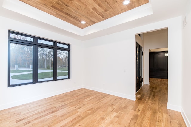 spare room with a raised ceiling, wooden ceiling, and light wood-type flooring