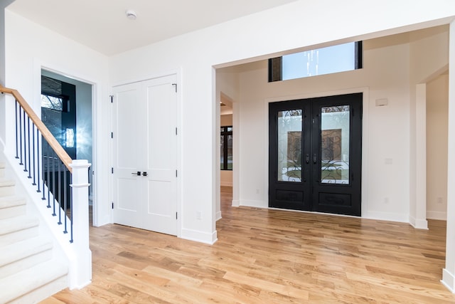 entryway with a wealth of natural light, light wood-type flooring, and french doors