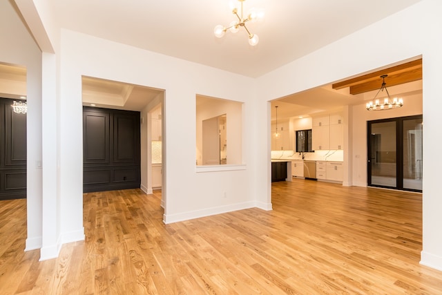 spare room featuring light wood-type flooring, an inviting chandelier, and a tray ceiling