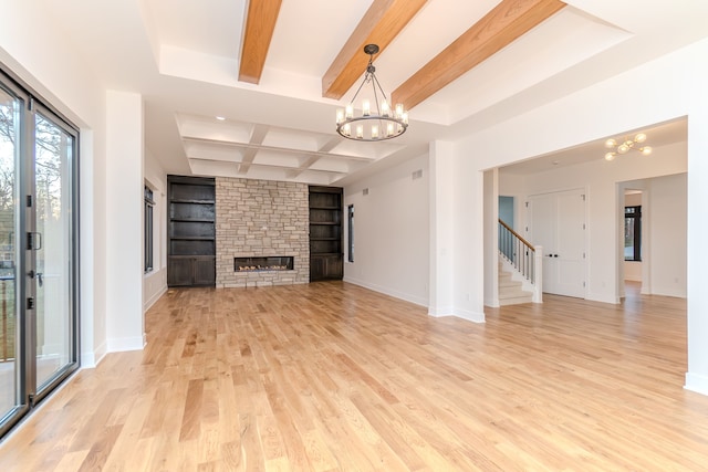 unfurnished living room with a fireplace, a notable chandelier, light hardwood / wood-style floors, beam ceiling, and built in shelves