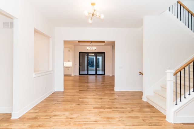 corridor featuring light wood-type flooring and a notable chandelier