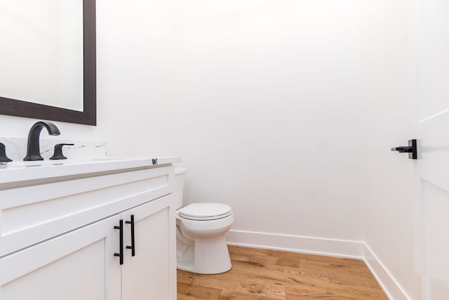 bathroom with vanity, toilet, and hardwood / wood-style floors