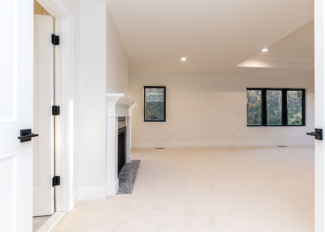 unfurnished living room with light colored carpet and a fireplace