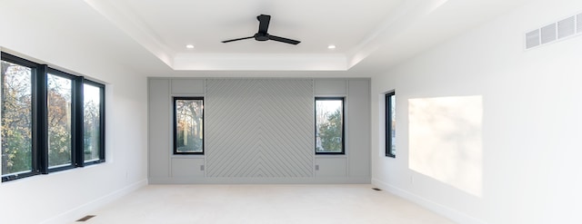 empty room featuring light colored carpet, ceiling fan, and a tray ceiling