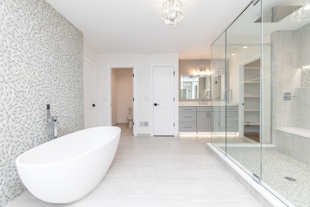 full bathroom featuring vanity, shower with separate bathtub, and toilet