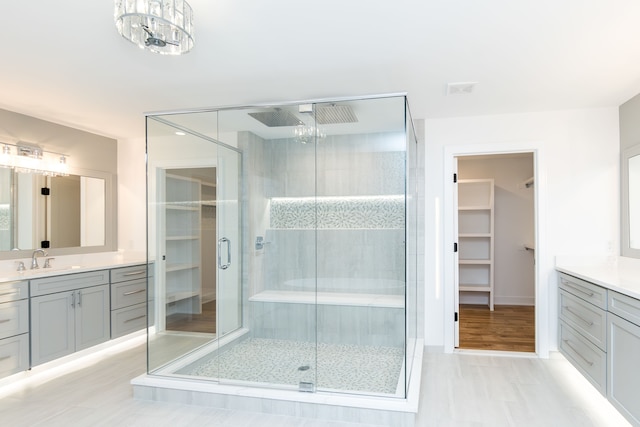 bathroom featuring a chandelier, vanity, and a shower with shower door