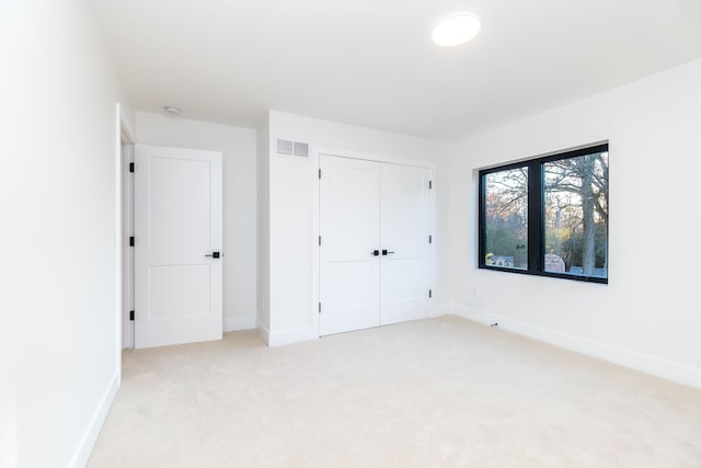 unfurnished bedroom featuring light colored carpet and a closet