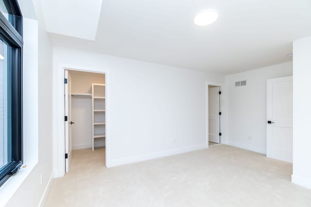 unfurnished bedroom with light colored carpet and a spacious closet