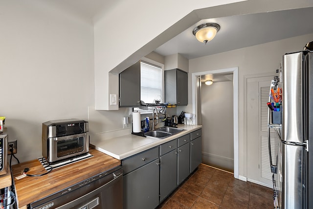 kitchen featuring dark tile patterned flooring, sink, gray cabinetry, and stainless steel fridge