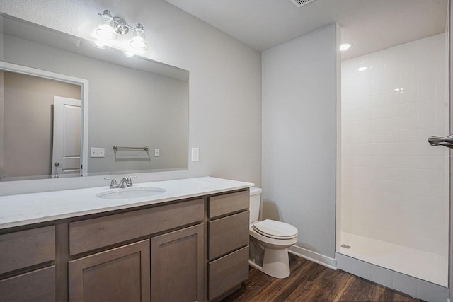 bathroom featuring wood-type flooring, toilet, vanity, and a shower