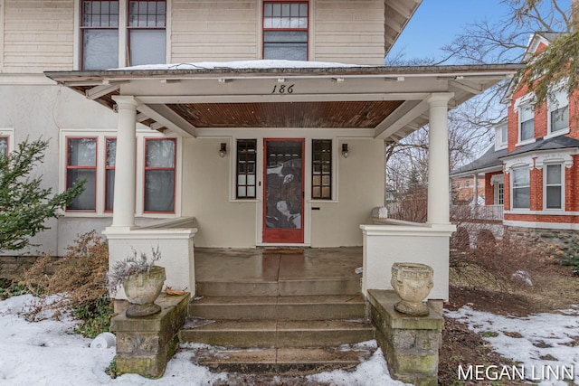 snow covered property entrance featuring a porch