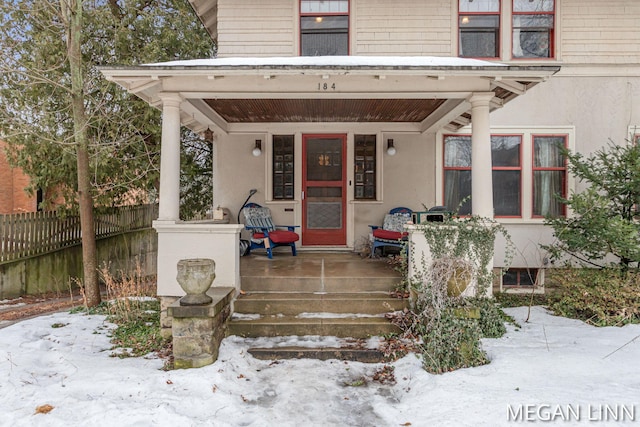 snow covered property entrance with covered porch