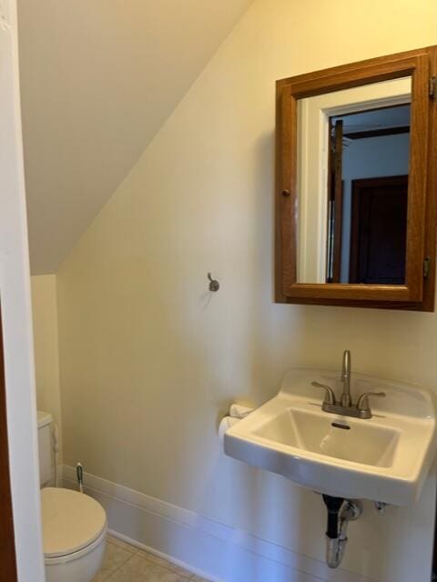 bathroom with vaulted ceiling, sink, tile patterned floors, and toilet