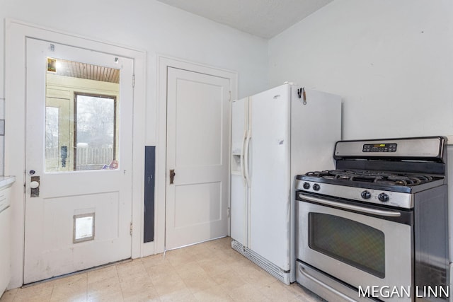 kitchen featuring stainless steel range with gas stovetop and white fridge with ice dispenser