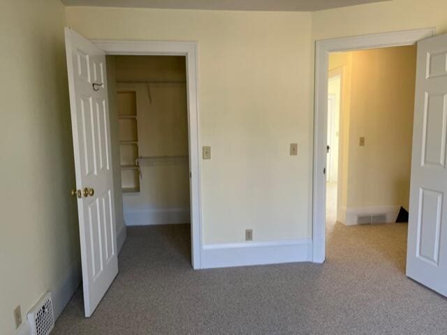 unfurnished bedroom featuring light carpet, a spacious closet, and a closet