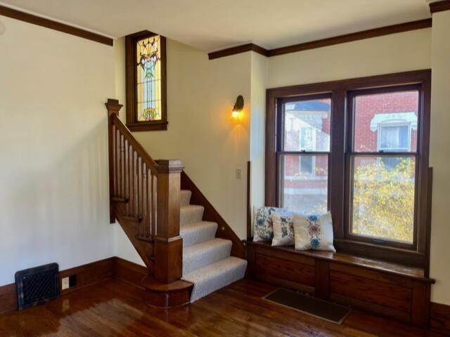 stairs with hardwood / wood-style flooring and ornamental molding